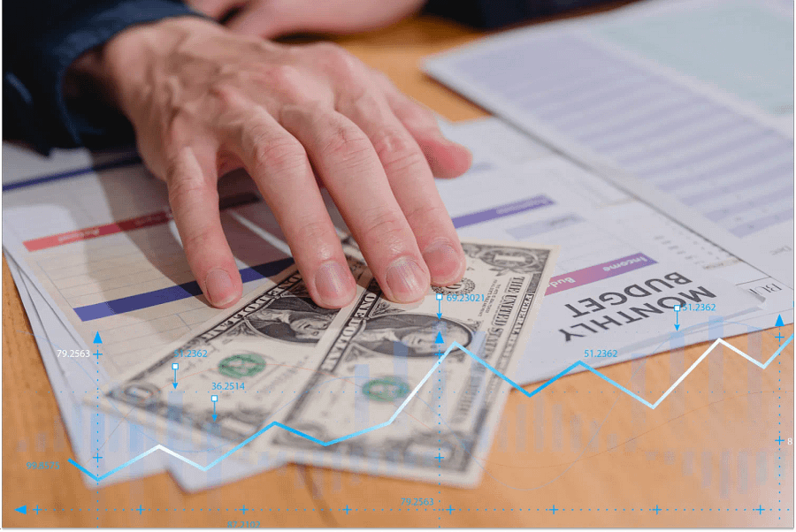 A hand showing dollar note with monthly budget planning, budget allocation for expenses and a budget for future retirement.