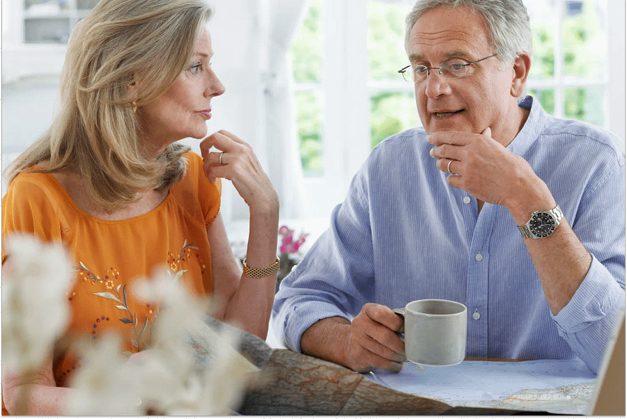 A matured couple sitting and discussing while holding a map and a laptop in front planning which states do not tax retirement income